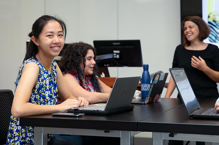 A group of young people sitting at a table with their laptops